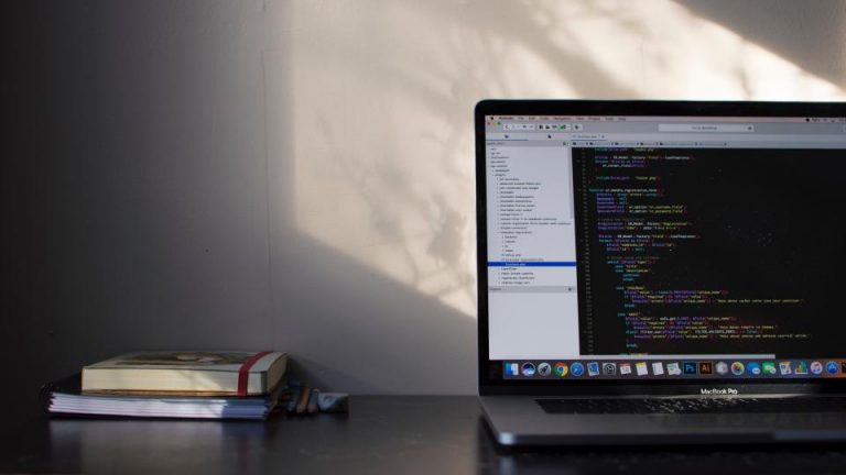 An open laptop on a desk in a low-lit workspace