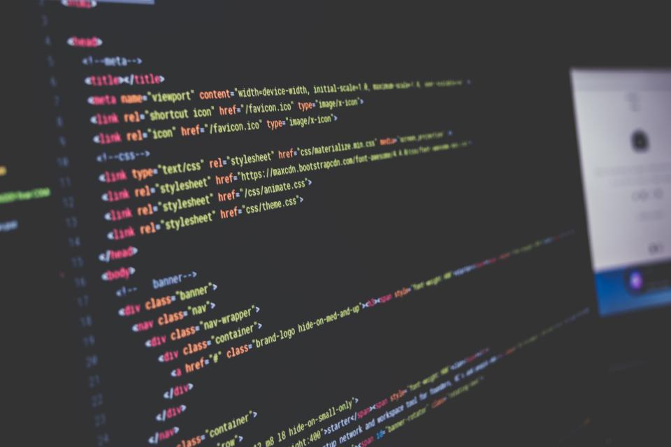 A practitioner reading code on a large monitor in a dark office
